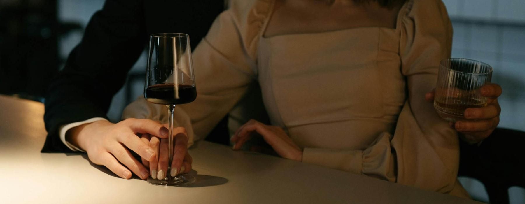 a man and woman sitting at a table with a glass of wine