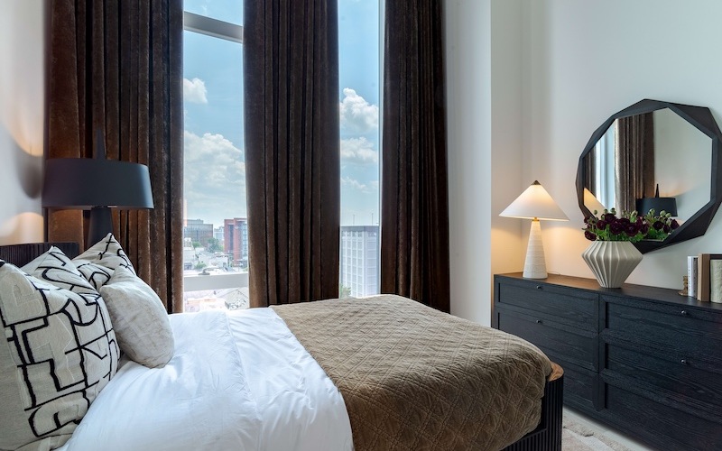 bedroom with windows overlooking city with curtains